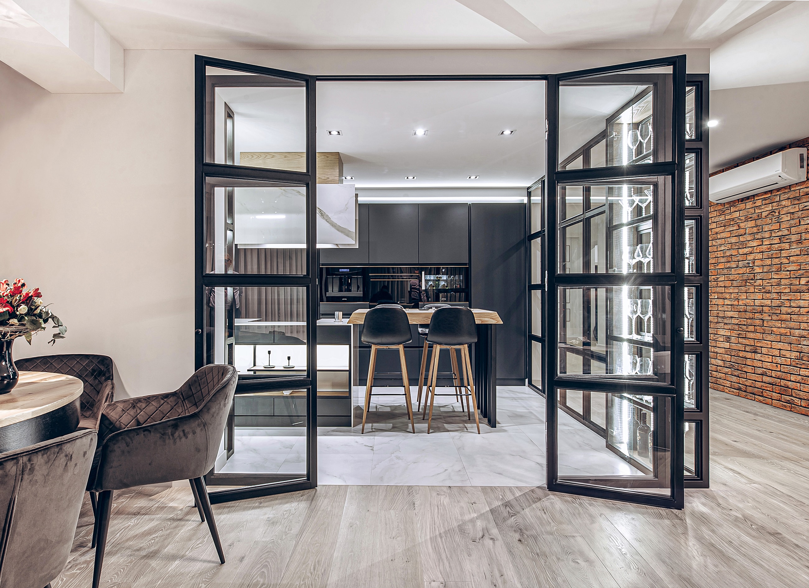 View from the living room: a blue sofa in the foreground, a glass display cabinet and open doors into the kitchen with its dining area