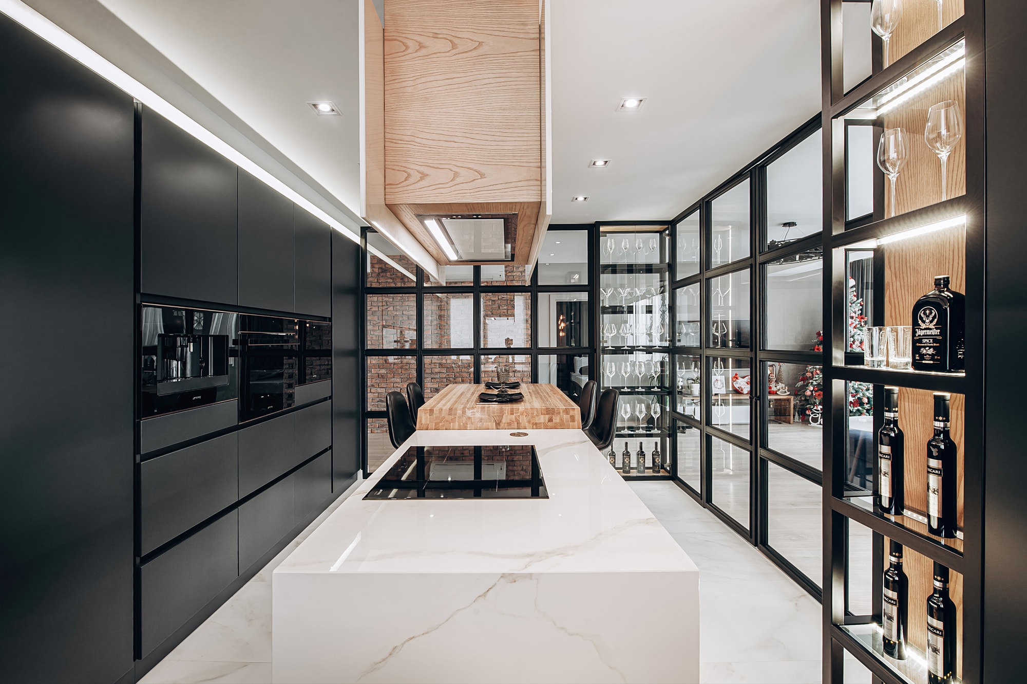 Кухня на заказ от WHAT Interiors: мраморный остров с варочной панелью, дубовая вытяжка и стеклянная перегородка на фоне кирпичной стены